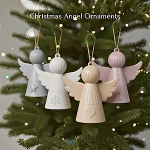 以下が含まれることがあります： クリスマスツリーに飾られた、グレー、白、ベージュ、ピンクの4つの天使のオーナメント。各天使は翼を持ち、星、雪の結晶、ハート、ベルなどの装飾が施されています。