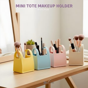 May include: Four colorful mini tote makeup holders in yellow, blue, pink, and cream, each filled with makeup brushes and products. The holders sit on a wooden surface, with the text "MINI TOTE MAKEUP HOLDER" at the top.