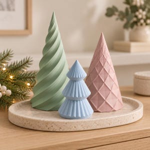 Puede incluir: Tres objetos decorativos en forma de cono sobre una bandeja circular moteada. Uno es una espiral alta de color verde salvia, otro es un cono mediano de color rosa empolvado con patr&oacute;n de rombos y otro es un cono peque&ntilde;o azul claro.