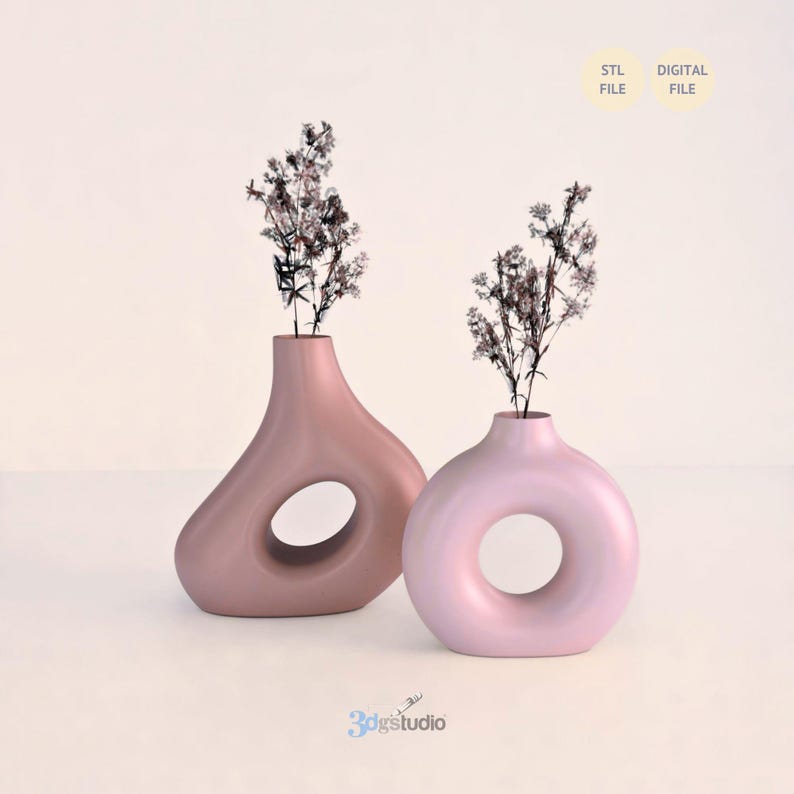 K&ouml;nnte beinhalten: Zwei moderne, minimalistische Vasen in Rosat&ouml;nen, jede mit Trockenblumenarrangements. Eine Vase hat eine einzigartige, asymmetrische Form mit einer gro&szlig;en zentralen &Ouml;ffnung, die andere ist kreisf&ouml;rmig. Die W&ouml;rter "STL FILE" und "DIGITAL FILE" sind sichtbar.