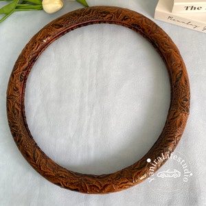Peut inclure: Housse de volant en cuir marron avec un motif floral en relief.