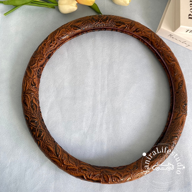 Peut inclure: Housse de volant en cuir marron avec un motif floral en relief.