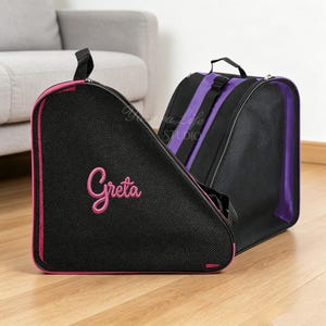 Könnte beinhalten: Zwei dreieckige Ausrüstungstaschen mit schwarzen Netzeinsätzen und Tragegriffen. Die vordere Tasche ist mit dem Namen Greta in rosa Garn bestickt. Die Taschen haben rosa beziehungsweise lila Zierleisten sowie Reißverschlüsse und Riemen.