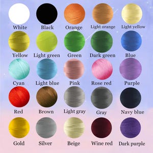 May include: A color chart titled Embroidery color options featuring twenty-five circular swatches of thread in various colors including white, black, orange, yellow, green, blue, cyan, pink, red, brown, gray, gold, silver, beige, and purple.