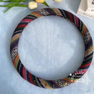 May include: A colorful patterned steering wheel cover with black, white, red, yellow, green, and purple stripes. The cover has the word "CUSTOM" written in gold letters.