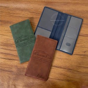 May include: Three leather car registration and insurance holders in green, brown, and blue. The green and brown holders have a car graphic and the text "REGISTRATION & INSURANCE". The brown holder is personalized with the name "Asher".