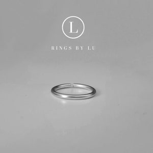 Op de afbeelding: Een eenvoudige zilveren ring met een glad, afgerond oppervlak. De ring is open en heeft aan één kant een kleine opening.