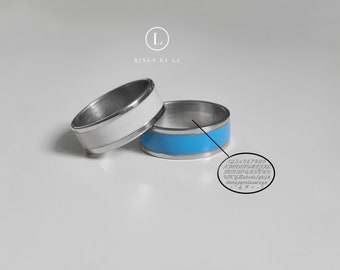 May include: Two silver rings with a white and blue enamel band. The blue ring has the numbers 1234567890 and the letters A-Z engraved on the inside.