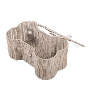 May include: A light beige woven basket shaped like a bone with a hinged lid. The basket features a metallic silver-tone latch on the front and a woven texture throughout, providing an open storage compartment with a distinct, elongated, curved design.