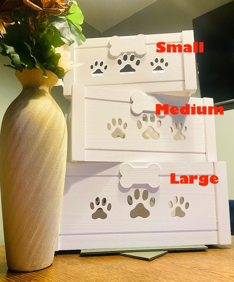 May include: Three white wooden dog crates stacked on top of each other. The crates are labeled "Small", "Medium", and "Large". Each crate has a bone-shaped handle and paw print cutouts.