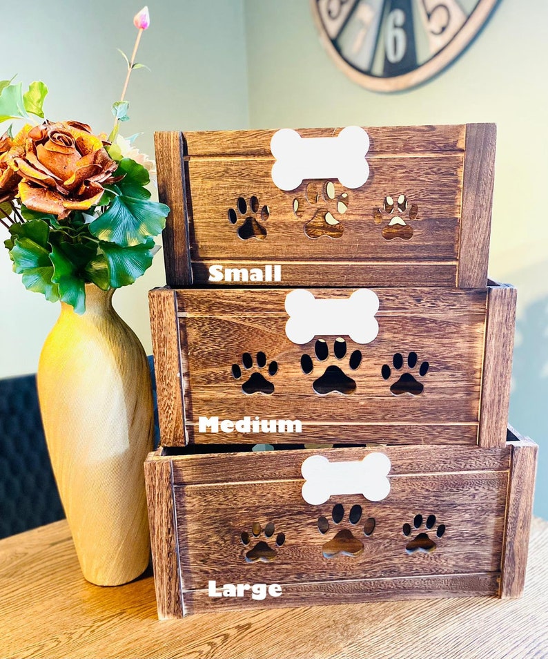 May include: Three wooden dog treat storage boxes with paw prints cutouts. The boxes are stacked from smallest to largest and labeled "Small", "Medium", and "Large".