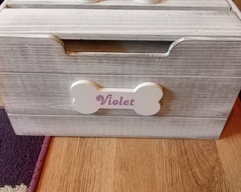 May include: White wooden toy box with a bone-shaped lid. The lid has a pink inscription that reads "Violet".