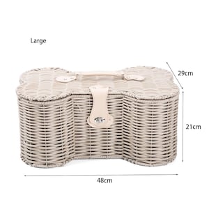 May include: A large bone-shaped wicker basket with a light beige finish, featuring a top handle and a central latch closure. The basket includes dimensions printed on the image, showing a width of 48 cm, a depth of 29 cm, and a height of 21 cm.