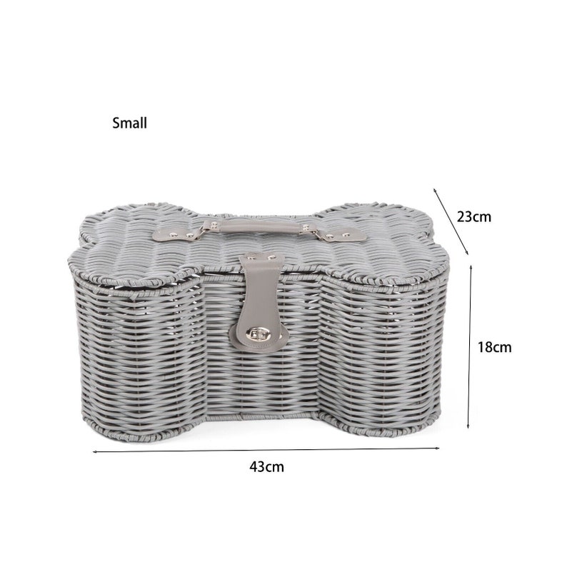 May include: A small grey woven wicker basket shaped like a bone with a grey handle and a central latch closure. The basket features dimensions of 43 cm in length, 18 cm in height, and 23 cm in width, as indicated by the text and arrows in the image.