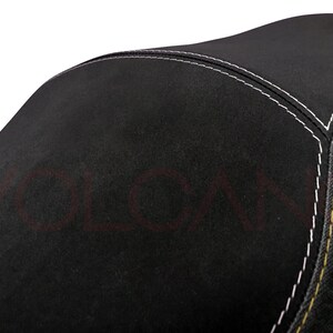 May include: Black motorcycle seat with white and yellow stitching.