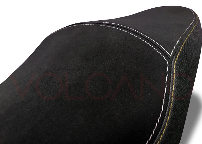 May include: Black motorcycle seat with white and yellow stitching.