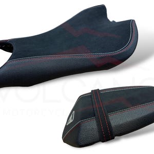 Puede incluir: Dos asientos de moto negros con dise&ntilde;os de rayos rojos y costuras blancas. Uno es m&aacute;s grande y contorneado, el otro m&aacute;s peque&ntilde;o y rectangular con una correa. Probablemente mejoras del mercado de accesorios.