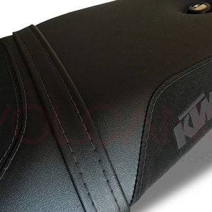 Puede incluir: Asiento de moto negro con un dise&ntilde;o cosido y un logotipo de KTM.