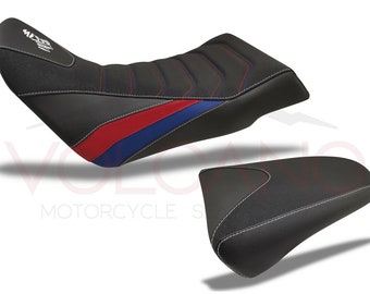 May include: A black motorcycle seat with red and blue stripes. The seat has a textured surface and is designed for comfort. The seat is also available in a smaller size for the passenger.