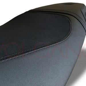 Puede incluir: Asiento de motocicleta negro con una superficie texturizada y una costura.