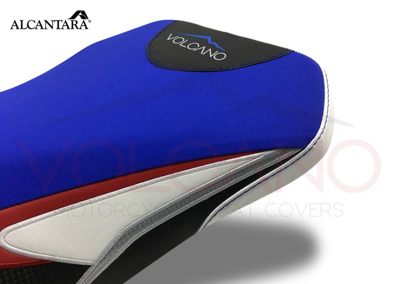 May include: Blue, red, white and black motorcycle seat cover with the word "VOLCANO" in white text on a black background.
