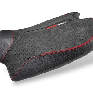 May include: A black motorcycle seat with red stitching. The seat has a textured surface with small perforations and a contoured shape. The word "V4" is visible in white on the seat.