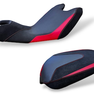 Puede incluir: Dos asientos de motocicleta. El asiento superior es negro con un centro gris perforado y detalles en rojo. El asiento inferior tiene un diseño a juego. Ambos asientos tienen costuras rojas.