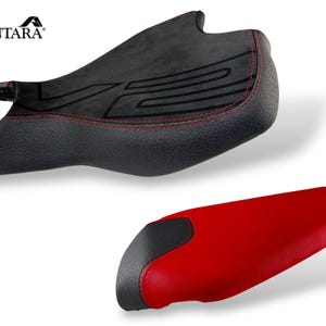 May include: Two motorcycle seat covers. The top seat is black with red stitching and a textured design. The bottom seat is red with a black accent. The brand name "ALCANTARA" is in the top left corner.