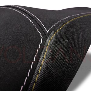 May include: Black motorcycle seat with white and yellow stitching.