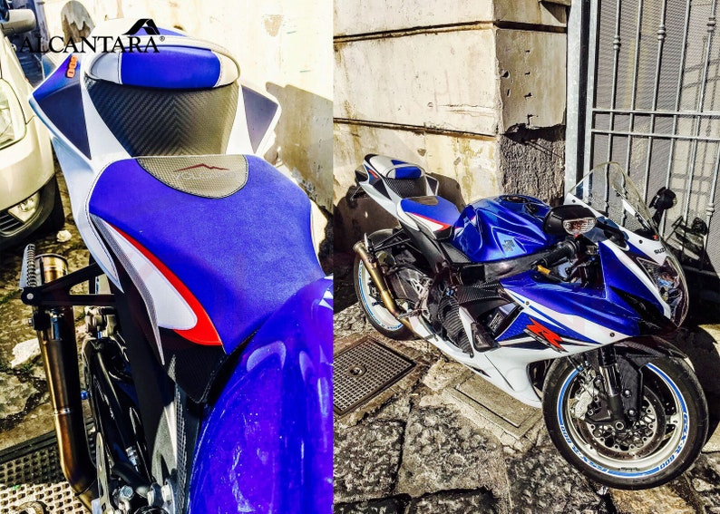 May include: A blue and white motorcycle with a custom seat featuring the Alcantara logo. The motorcycle is parked on a cobbled street.