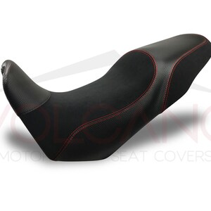 Può includere: Sella da moto nera con cuciture rosse e look in fibra di carbonio. La sella è progettata per il comfort e le prestazioni.
