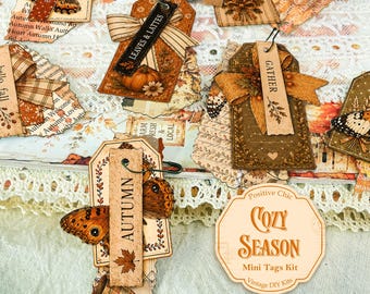 May include: A collection of decorative paper tags featuring autumn themes, butterflies, pumpkins, and plaid bows. The tags include printed text such as Enjoy Today, Leaves & Lattes, Gather, and Autumn. A circular label reads Positive Chic Cozy Season Mini Tags Kit.