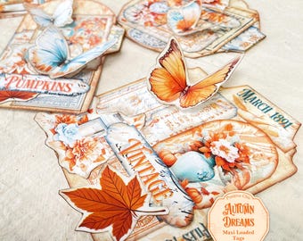 Op de afbeelding: Een verzameling decoratieve papieren labels met herfstthema-illustraties van oranje vlinders, esdoornbladeren, pompoenen en bloemstukken. De labels bevatten teksten zoals PUMPKINS, MARCH 1891, VINTAGE en AUTUMN DREAMS.