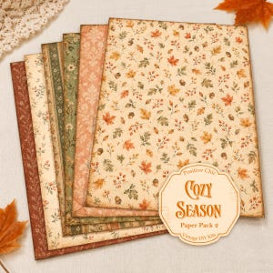 May include: A set of rectangular decorative paper sheets featuring various autumn-themed patterns including fall leaves, acorns, berries, and floral motifs in shades of orange, green, and cream. A label reads Positive Chic COZY SEASON Paper Pack 2.