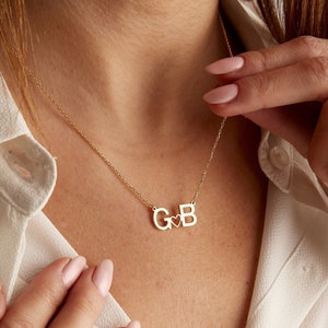 May include: Gold necklace with a heart charm and the letters "G" and "B" intertwined.