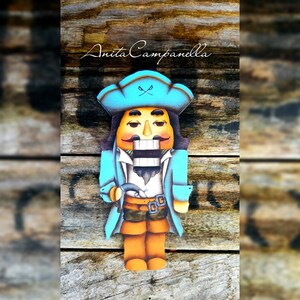 Puede incluir: Un cascanueces de madera pintado para parecer un pirata. Lleva un sombrero azul con una calavera y huesos cruzados, una chaqueta azul, una camisa blanca y pantalones marrones. Sostiene una espada en su mano derecha.