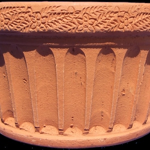 Può includere: Un vaso di terracotta con un bordo decorativo e lati scanalati.