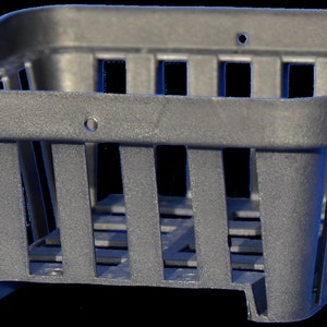 Könnte beinhalten: Ein quadratischer Pflanzentopf aus schwarzem Kunststoff mit einem Gittermuster. Der Topf hat einen quadratischen Boden und eine quadratische Oberseite mit einem Rand.