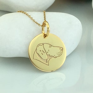 Può includere: Collana d'oro con un ciondolo rotondo con la silhouette di un cane incisa.