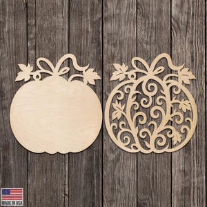 May include: Two unfinished wooden pumpkin cutouts. One is a solid pumpkin shape, and the other is a pumpkin with an intricate, openwork design. Both have a stem and leaves at the top. The background is a rustic wooden surface.