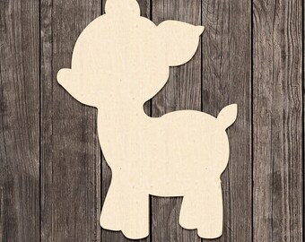 May include: A wooden cutout of a deer in a standing pose. The deer is light beige and has a simple, cartoon-like design. The cutout is placed on a wooden background with vertical planks. The words "MADE IN USA" are in the bottom left corner.