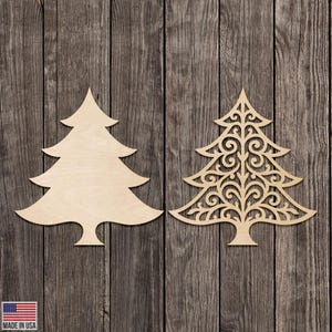 May include: Two wooden Christmas tree cutouts. One is a solid tree shape, the other is a decorative tree with an open, swirling design. Both are made of light-colored wood and are displayed against a rustic wood background.