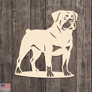 Może przedstawiać: Drewniana sylwetka psa rasy Rottweiler. Pies stoi, zwrócony w prawo, ze szczegółowymi wycięciami definiującymi jego cechy. Sylwetka jest jasnobrązowa na tle ciemnego usłojenia drewna. Napis "MADE IN USA" znajduje się w lewym dolnym rogu.