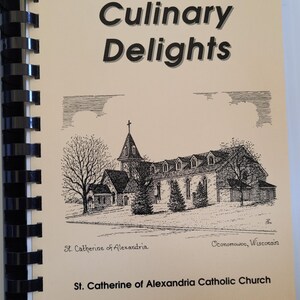 May include: A spiral-bound cookbook titled "Culinary Delights." The cover features a black and white illustration of a church, with the text "St. Catherine of Alexandria Catholic Church" below. The book's binding is black.