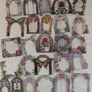 May include: A selection of decorative stickers with stained glass window and butterfly designs. The stickers feature floral arrangements, including roses, in shades of pink, blue, and green. The designs are reminiscent of traditional stained glass.