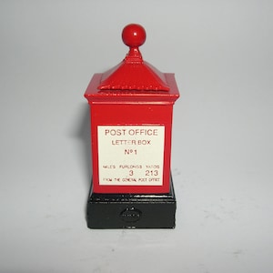May include: Red post office letter box with a black base and a gold finial. The box has a white label that reads "POST OFFICE LETTER BOX N°1" and "MILES FURLONGS YARDS 3 213 FROM THE GENERAL POST OFFICE".