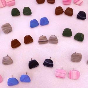 Könnte beinhalten: Sortiment an bunten, gemusterten und strukturierten Ohrringen aus Polymer Clay. Die Ohrringe haben verschiedene Formen, darunter quadratisch, rechteckig und oval. Die Farben umfassen Pink, Blau, Grün, Braun und Grau.