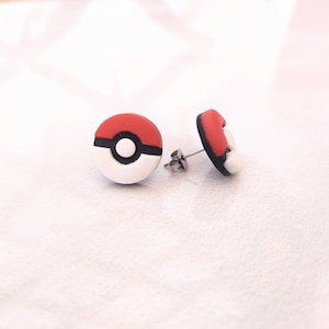 Op de afbeelding: Een paar rode, witte en zwarte Pokeball oorbel studs. De oorbellen zijn gemaakt van polymer clay en hebben een zilveren post.