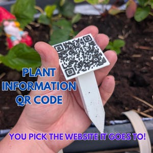 Op de afbeelding: Een witte plantenmarker met een QR-code en de tekst "PLANT INFORMATION QR CODE". De marker wordt in een hand gehouden, met de tekst "YOU PICK THE WEBSITE IT GOES TO!" onderaan. De achtergrond toont aarde en planten.