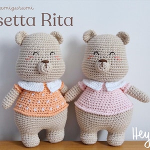 May include: Two crocheted teddy bears, each with a smiling face, blush, and a brown nose. One bear wears an orange shirt with white polka dots, the other a pink shirt. Both have white collars. Text reads "Schema amigurumi Orsetta Rita."